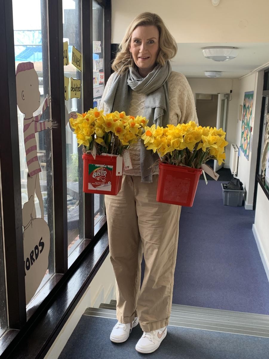 A happy lady holding two buckets of daffodils